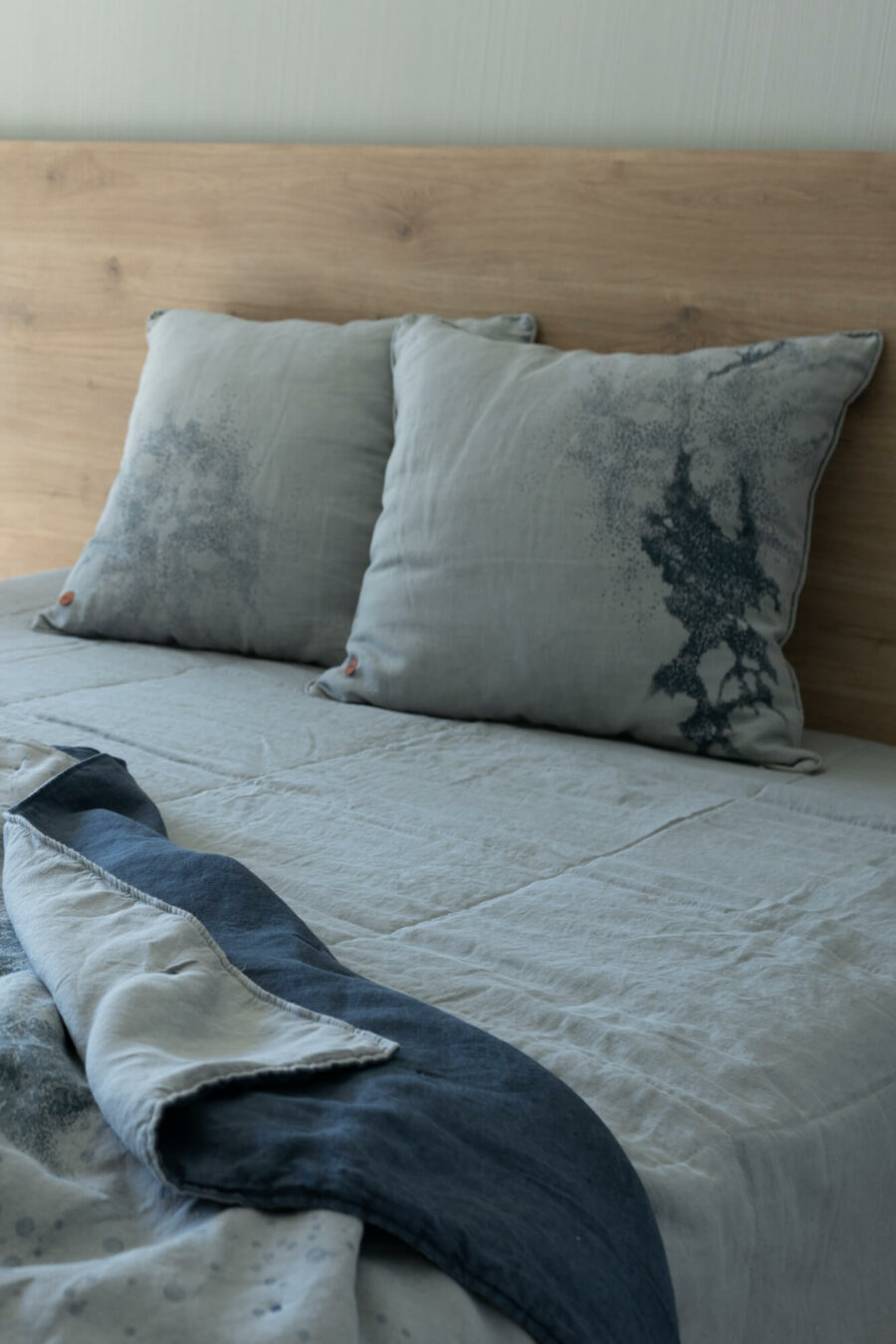 Lniana narzuta i lniane poduszki poppy leżą na łóżku.