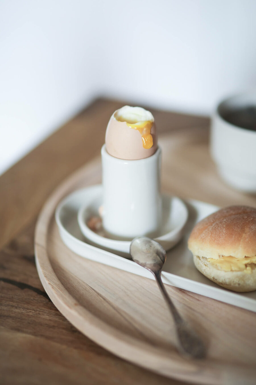 porcelanowe naczynie do jajka Ponds z jajkiem na miękko stoi na półmisku porcelanowym Ponds.