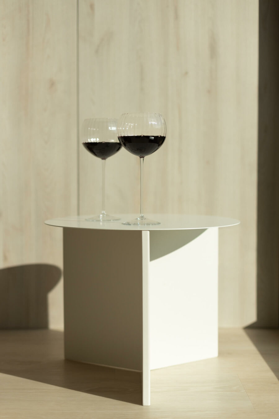 Na stoliku stoją dwa szklane, bezbarwne kieliszki do czerwonego wina.