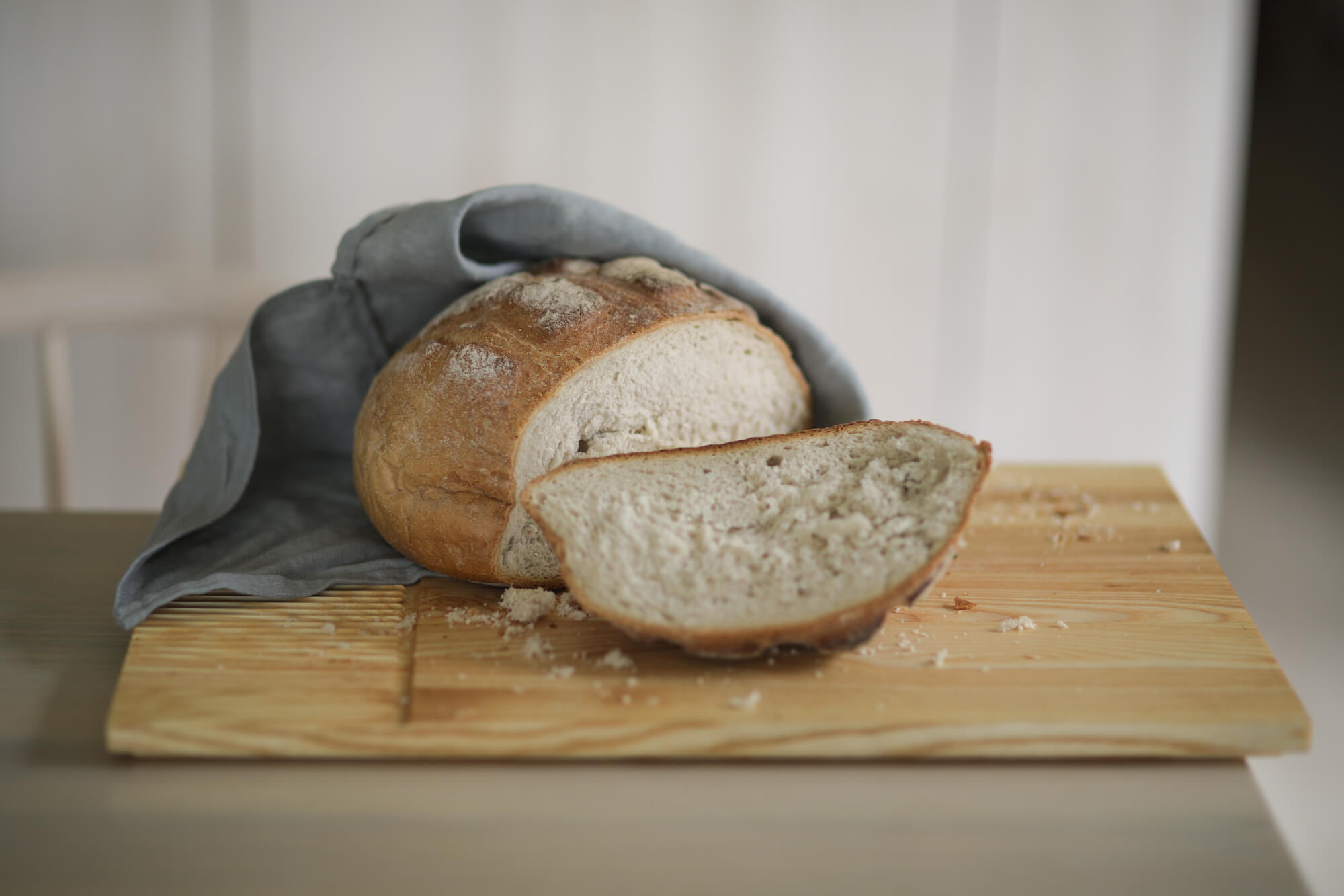 Na desce do krojenia i serwowania Fields leży ukrojony kawałek chleba owiniętego w lniany worek.