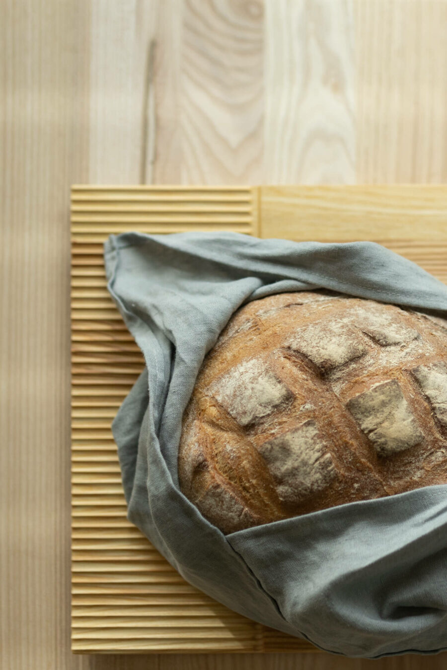 Na desce do krojenia i serwowania Fields leży okrągły chleb owinięty lnianym workiem.