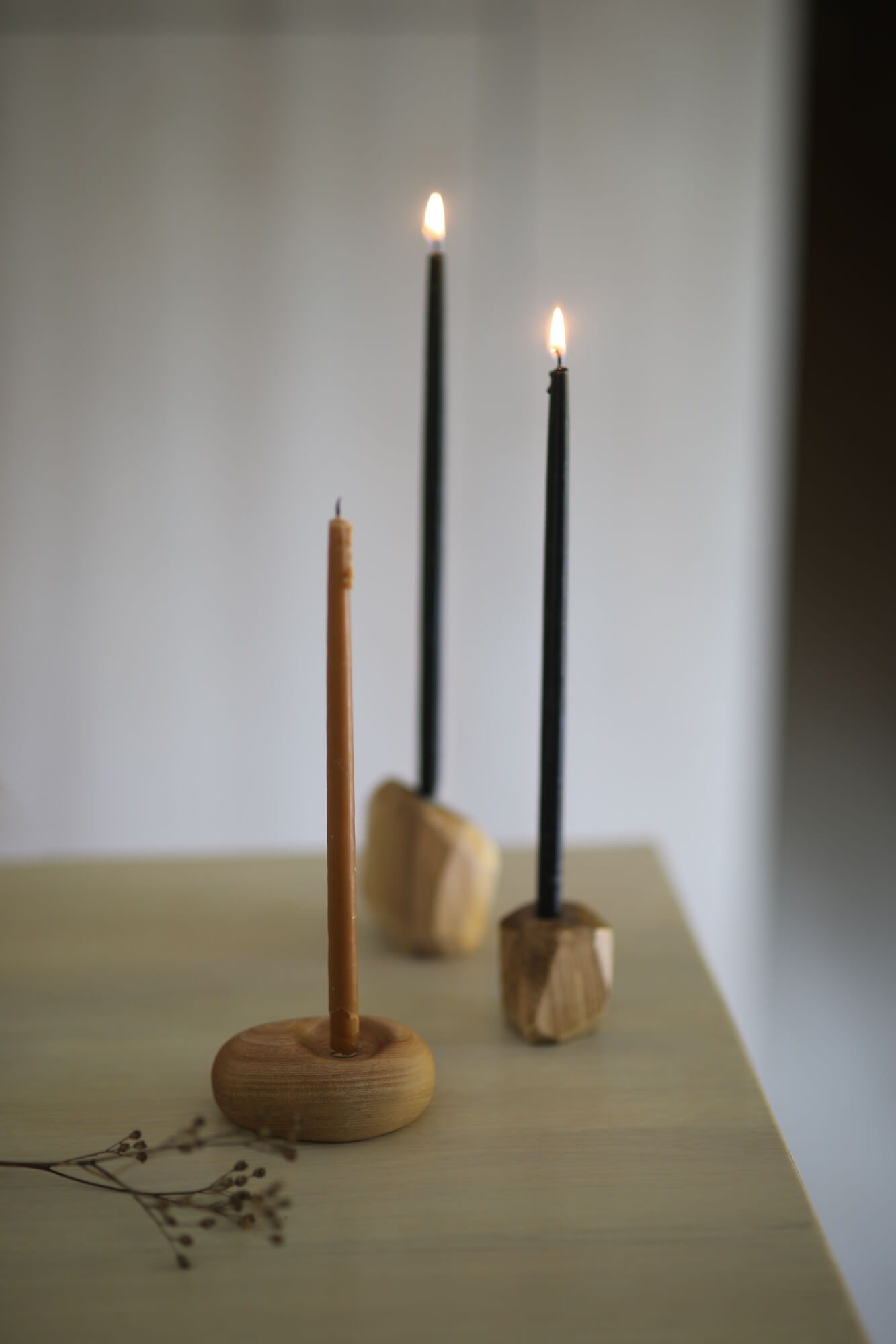 Na stole, w trzech drewnianych, pojedynczych świecznikach stoją świece. Dwie się palą.