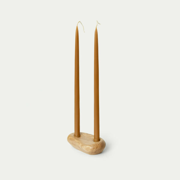W drewnianym świeczniku stoją dwie świece z naturalnego wosku pszczelego.