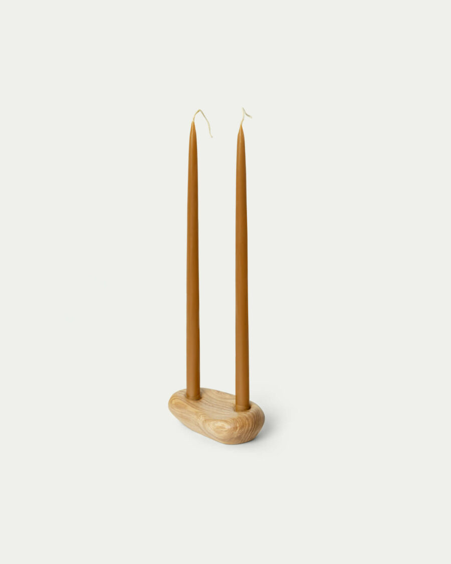 W drewnianym świeczniku stoją dwie świece z naturalnego wosku pszczelego.